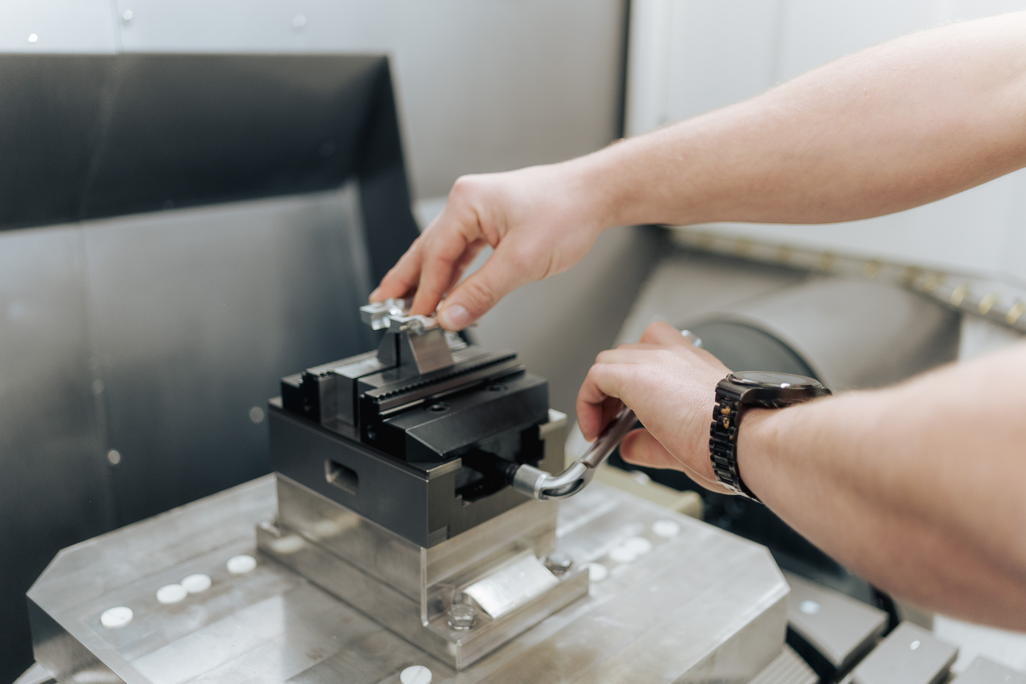 Mitarbeiter spannt Werkstück in CNC-Maschine ein