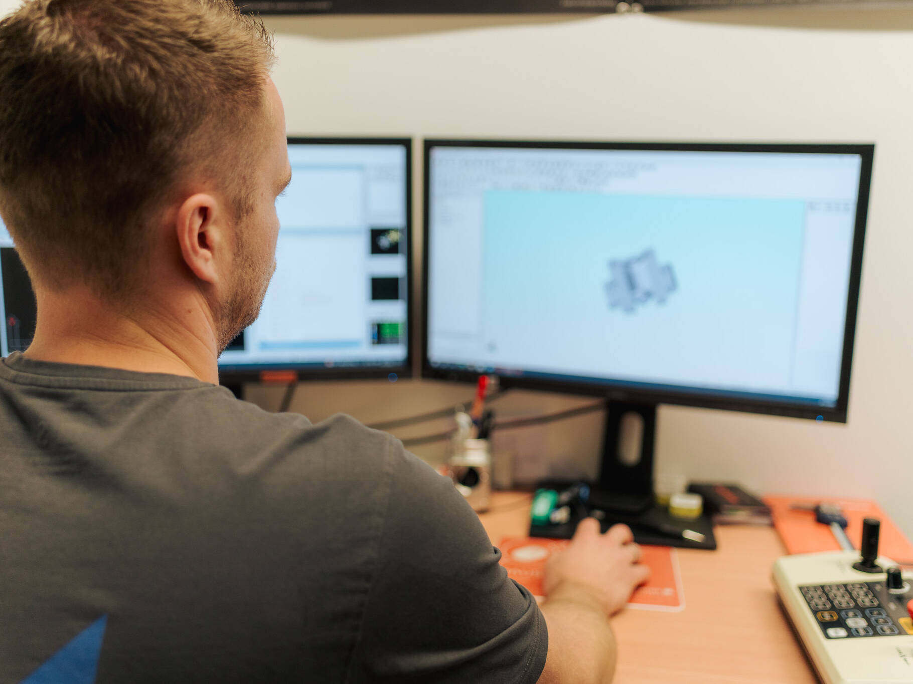 Mitarbeiter arbeitet mit CAD/CAM-Software an zwei Monitoren