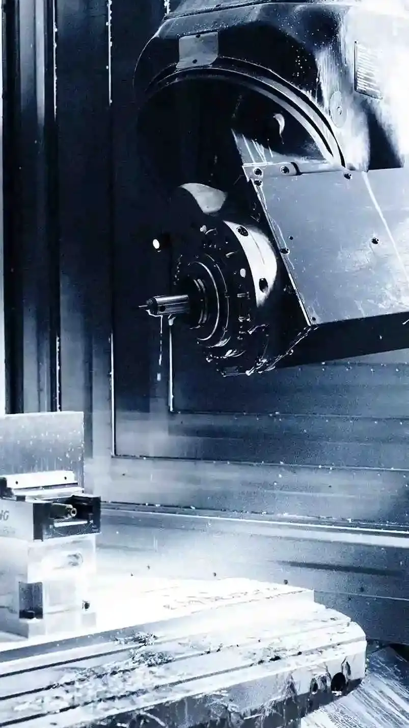 Nahaufnahme einer CNC-Fräsmaschine mit eingespanntem Metallwerkstück und Fräskopf, umgeben von Metallspänen und Kühlflüssigkeit